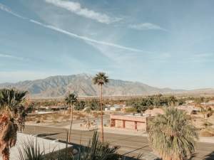 Stunning desert landscape in Palm Springs, CA, featuring mountains, palm trees, and clear skies.