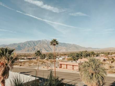 Stunning desert landscape in Palm Springs, CA, featuring mountains, palm trees, and clear skies.