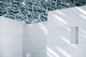 Sunlit geometric patterns in the Louvre Abu Dhabi's interior design.