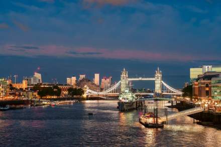 Stunning night view of Tower Bridge illuminated over the River Thames in London, showcasing the city's skyline.
