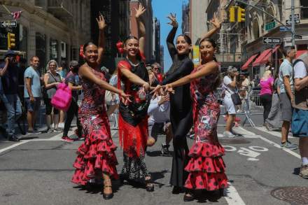 Flamenco dancers in colorful dresses performing at a street festival in New York City.