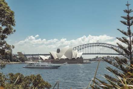 Beautiful view of Sydney Opera House and Harbor Bridge with a yacht sailing in the foreground.