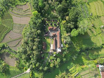 Explore an aerial view of a Balinese temple nestled amidst green rice terraces in Selat, Bali, Indonesia.