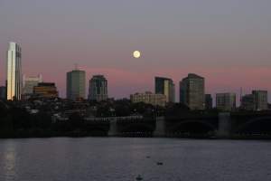 Stunning view of the Boston skyline with a full moon over the Charles River at twilight.