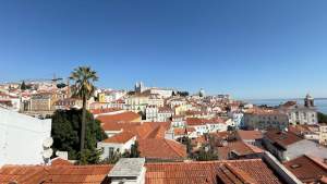 Experience the vibrant landscape of Lisbon with its iconic red tiled rooftops under a clear blue sky.