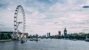 Scenic view of the London Eye on the River Thames with clear blue skies and city skyline.