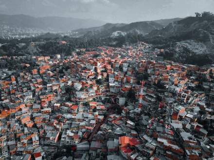 Colorful urban landscape of Medellín viewed from above, showcasing dense housing and surrounding hills.
