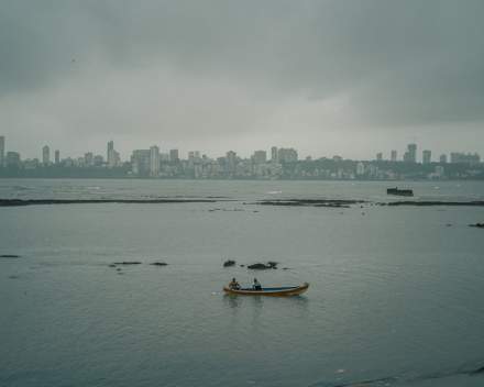 A serene boat ride near Mumbai's skyline on a calm, overcast day, capturing urban and natural beauty.