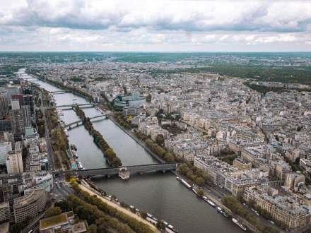 Stunning aerial view of Paris showcasing the Seine River and intricate cityscape under a cloudy sky.