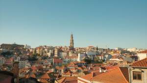 Panoramic view of Porto's historic district showcasing red rooftops and the iconic Clerigos Tower under a clear blue sky.