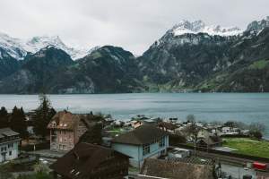 A stunning aerial view of a Swiss village by a lake, surrounded by snow-capped mountains.