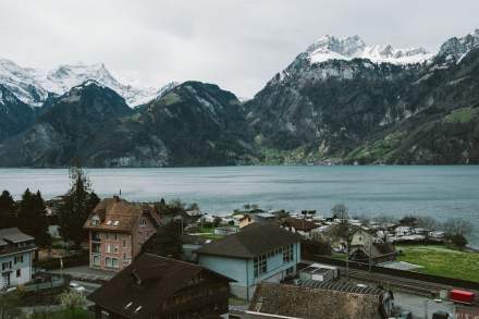 A stunning aerial view of a Swiss village by a lake, surrounded by snow-capped mountains.