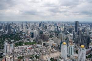 Stunning aerial view of Bangkok's modern skyline under clouded skies.