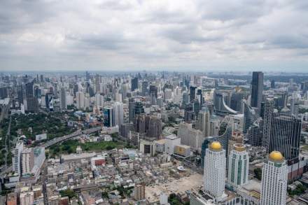 Stunning aerial view of Bangkok's modern skyline under clouded skies.