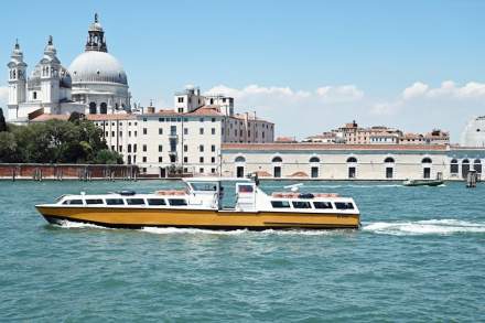 A vibrant water taxi travels past the iconic Santa Maria della Salute in Venice, Italy.