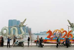 People preparing for Lunar New Year 2026 by a dragon statue along a lakeside.