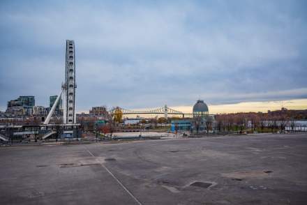 Scenic view of Montréal's Old Port with a Ferris wheel and urban skyline under a serene sky.