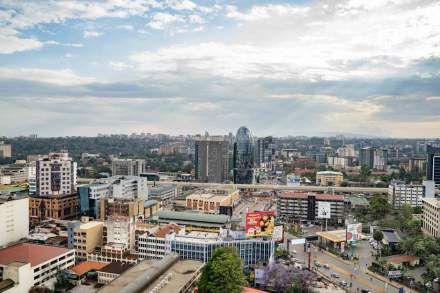 A vibrant aerial shot of Nairobi's bustling cityscape with modern architecture under a partly cloudy sky.