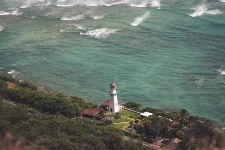 Stunning aerial view of Diamond Head Lighthouse surrounded by ocean and greenery in Honolulu, Hawaii.